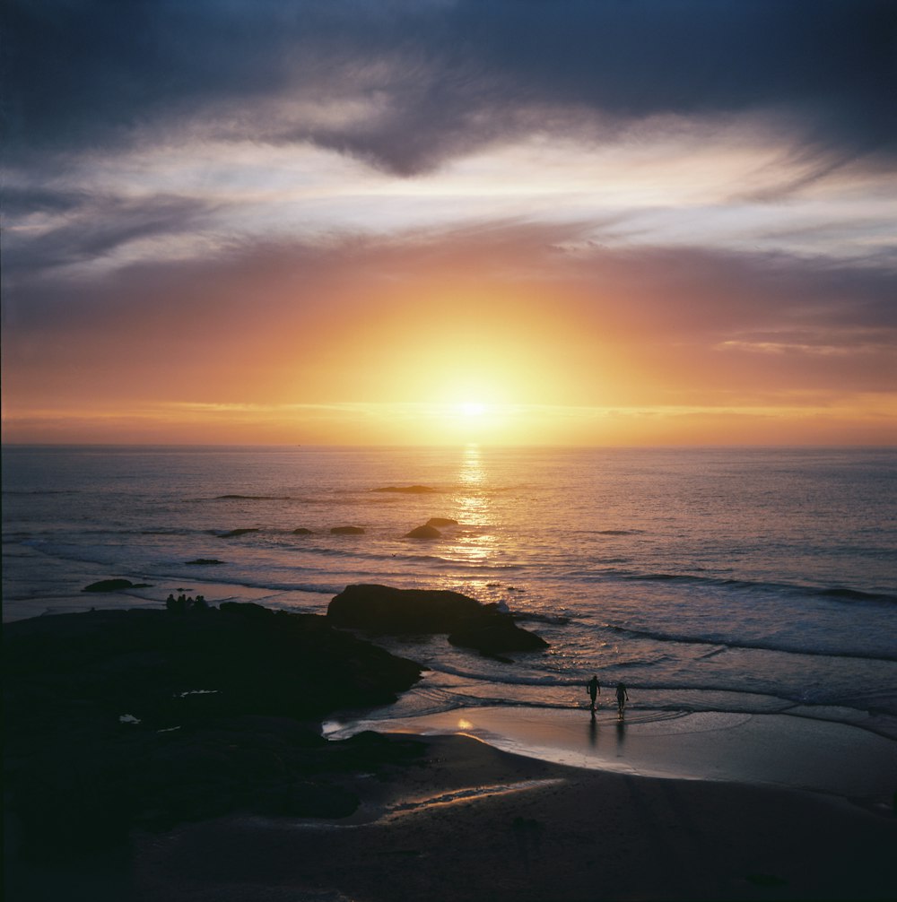 the sun is setting over the ocean on a cloudy day