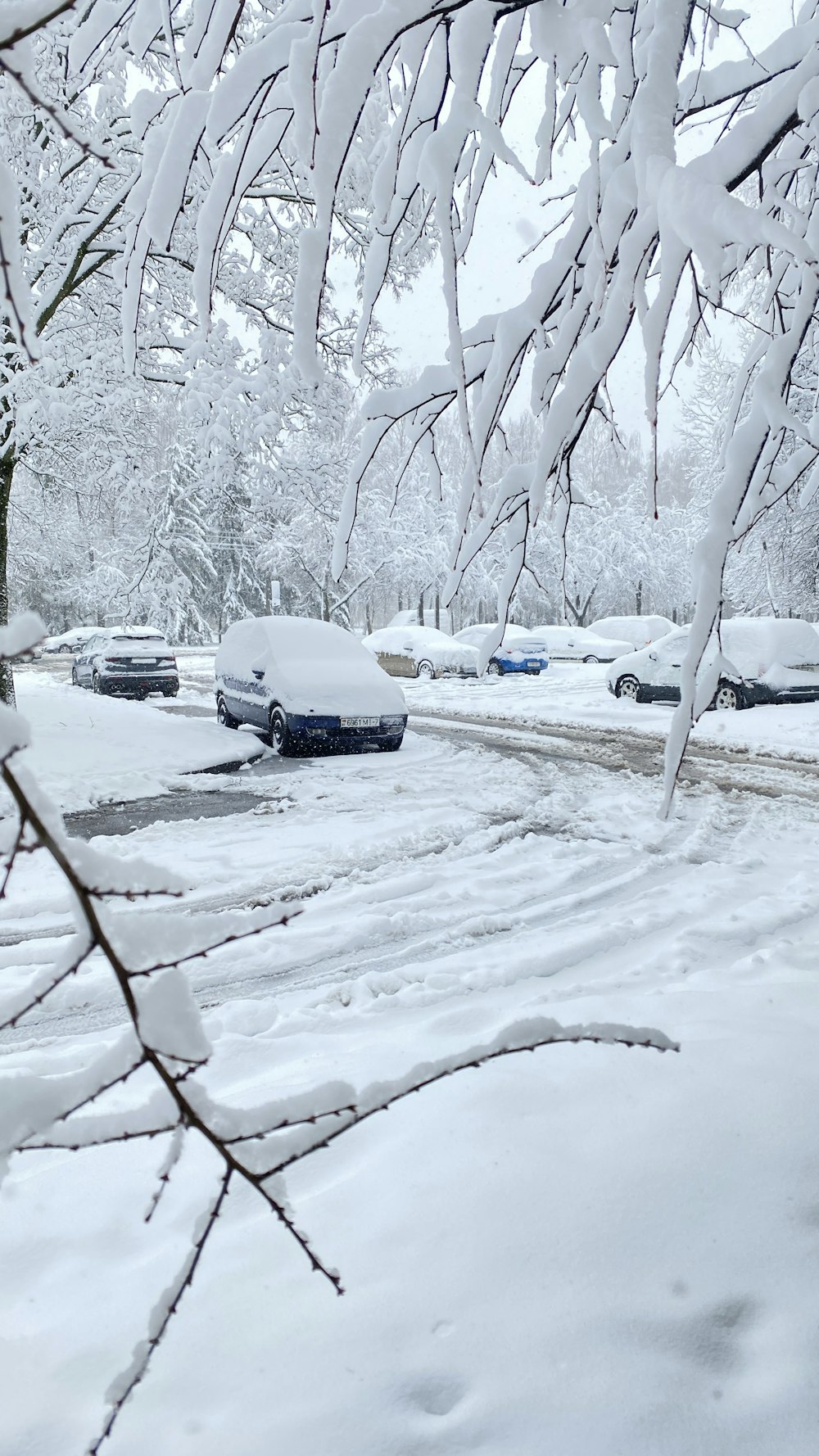 a snow covered street with cars parked on it