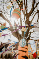 Soft sunlight filtering through translucent Easter egg decorations hanging from tree branches.