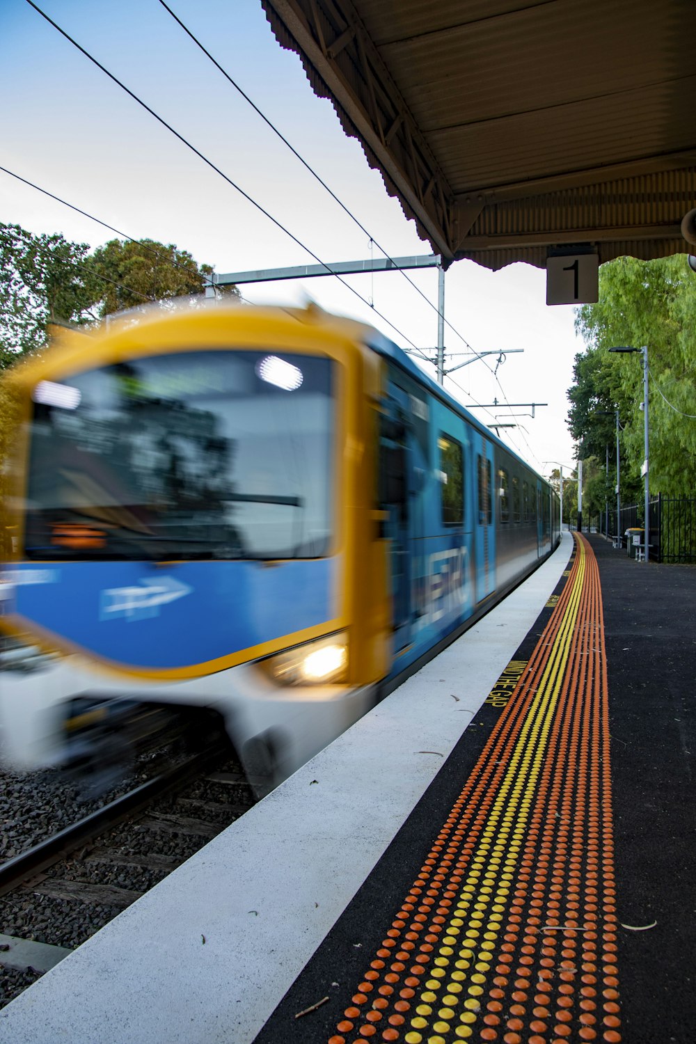 a blue and yellow train traveling past a train station