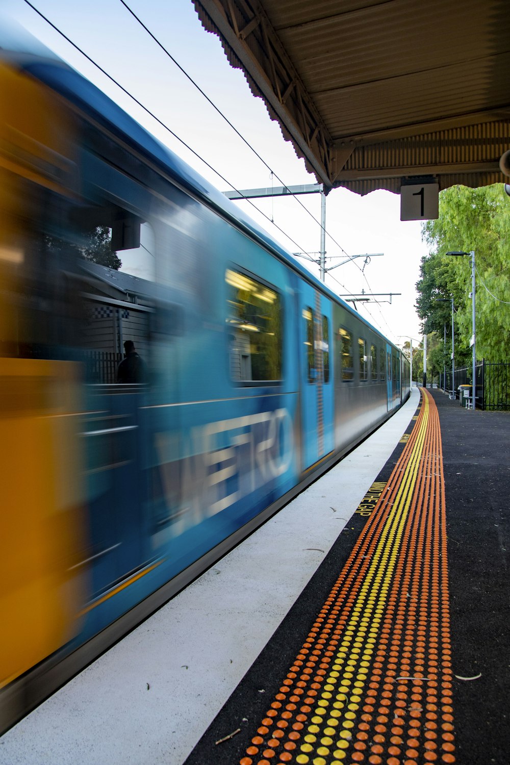 a blue and yellow train traveling past a train station