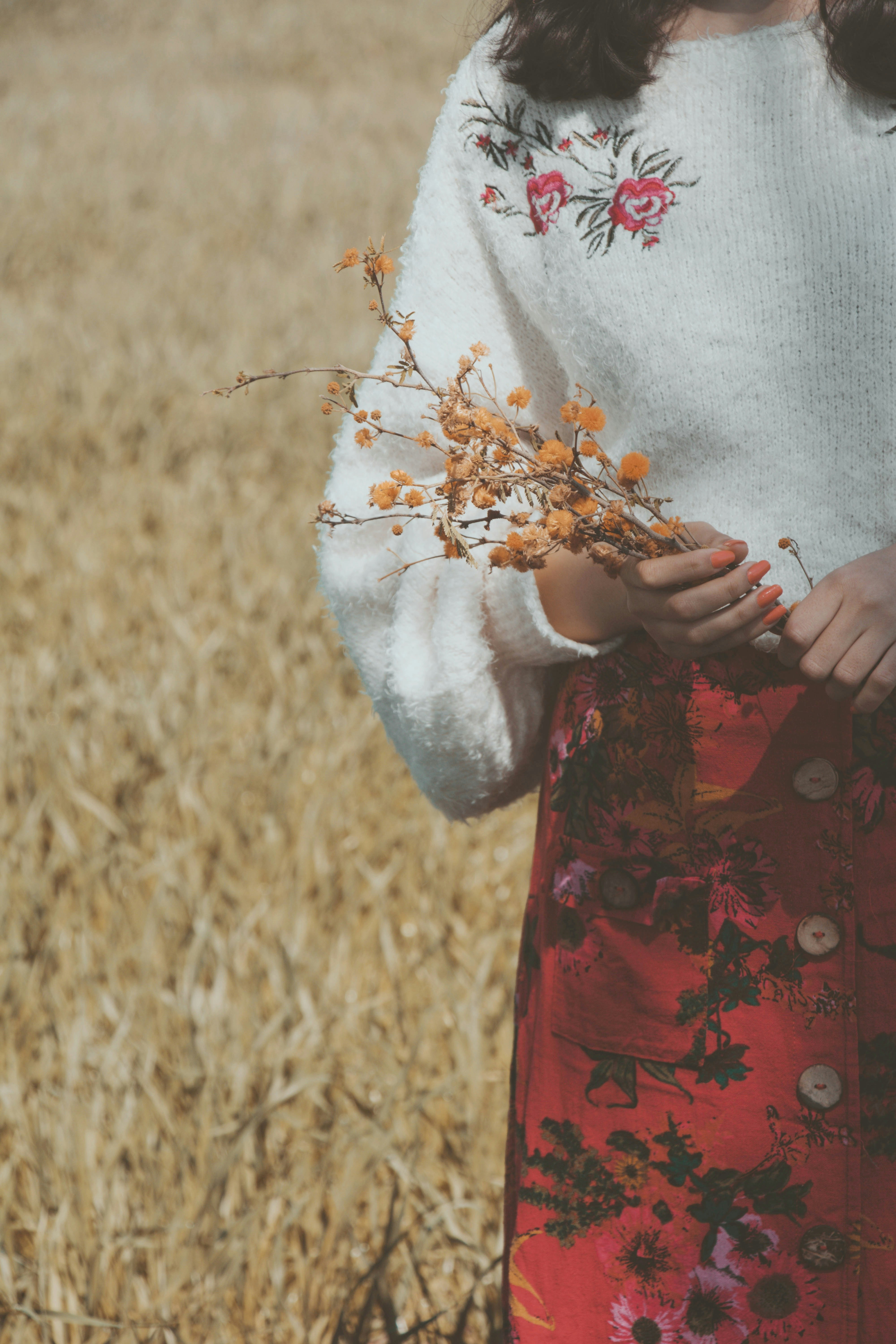 a woman standing in a field holding a bouquet of flowers