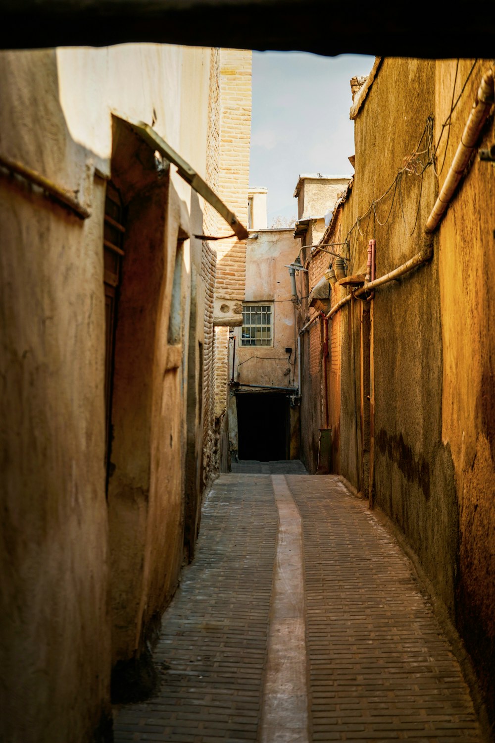 a narrow alley way with a clock tower in the background