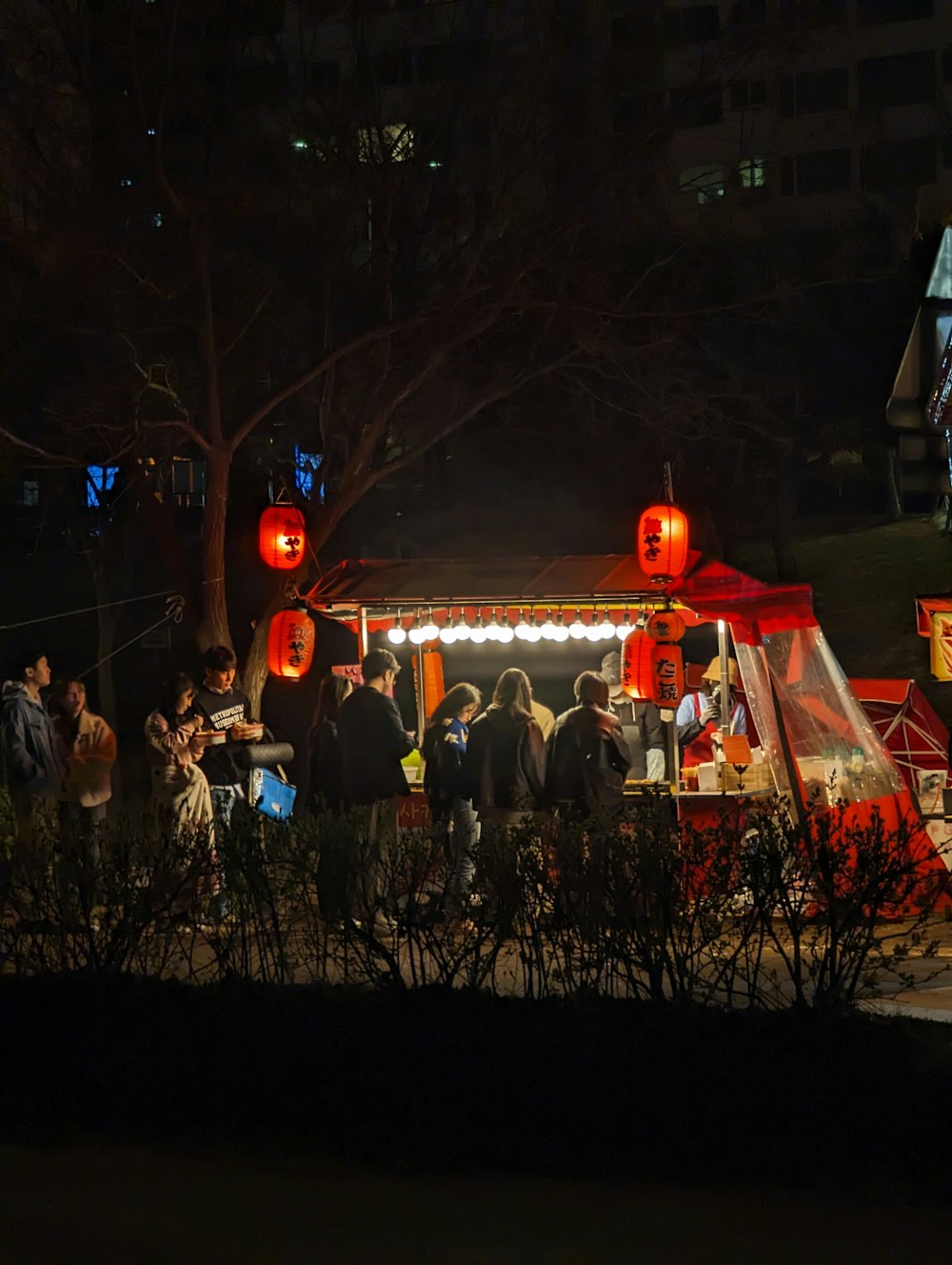 a group of people standing around a booth at night
