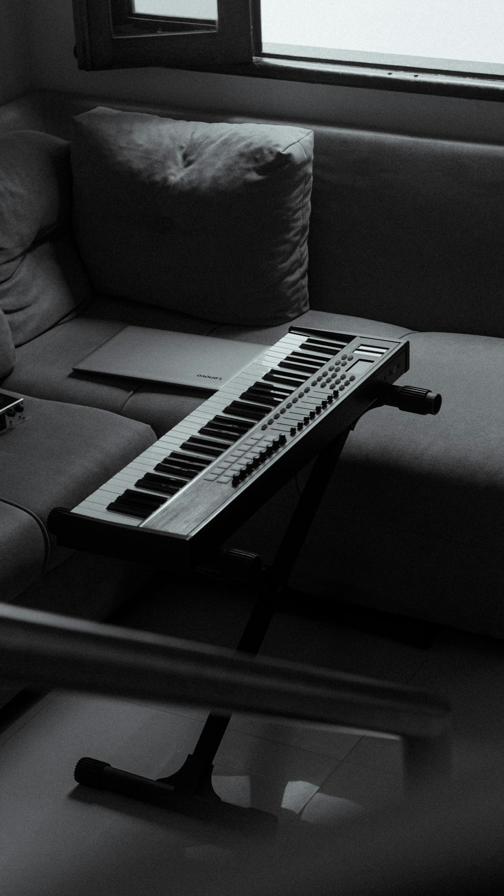 a keyboard sitting on top of a couch next to a window