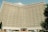 A large hotel building with a concave facade covered in numerous identical rectangular windows. The structure is prominently labeled 'Hotel Uzbekistan' at the top and has a symmetrical, grid-like pattern.
