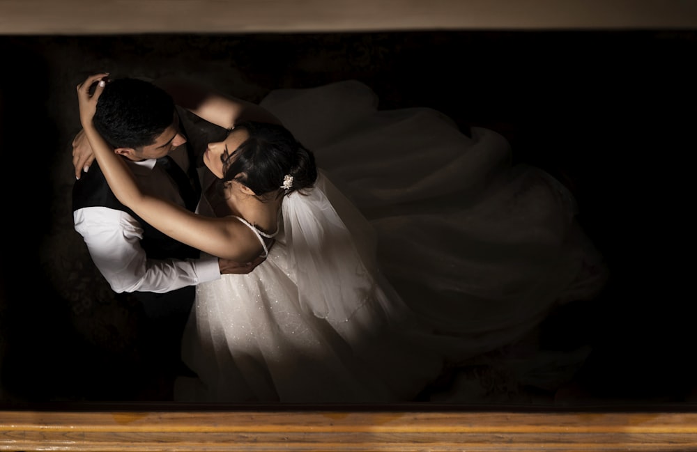 a bride and groom dance together in a dark room