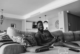 Smiling man receiving money notification on his phone in a modern home setting.