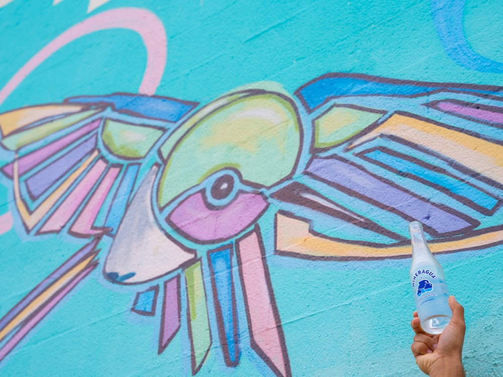 a person holding a bottle of water in front of a wall