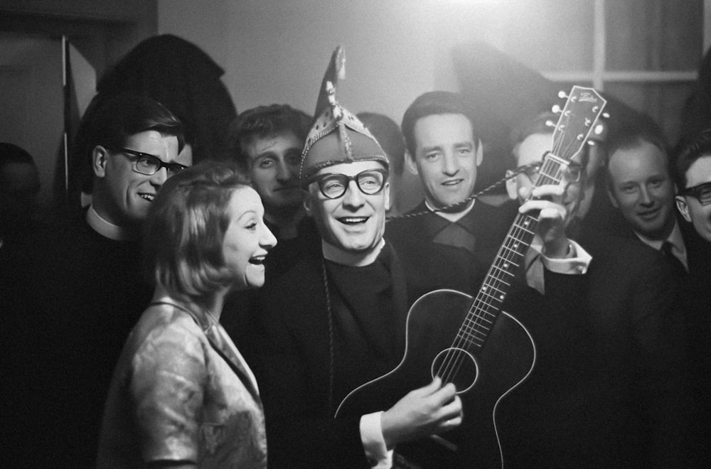 a group of people standing around a man holding a guitar