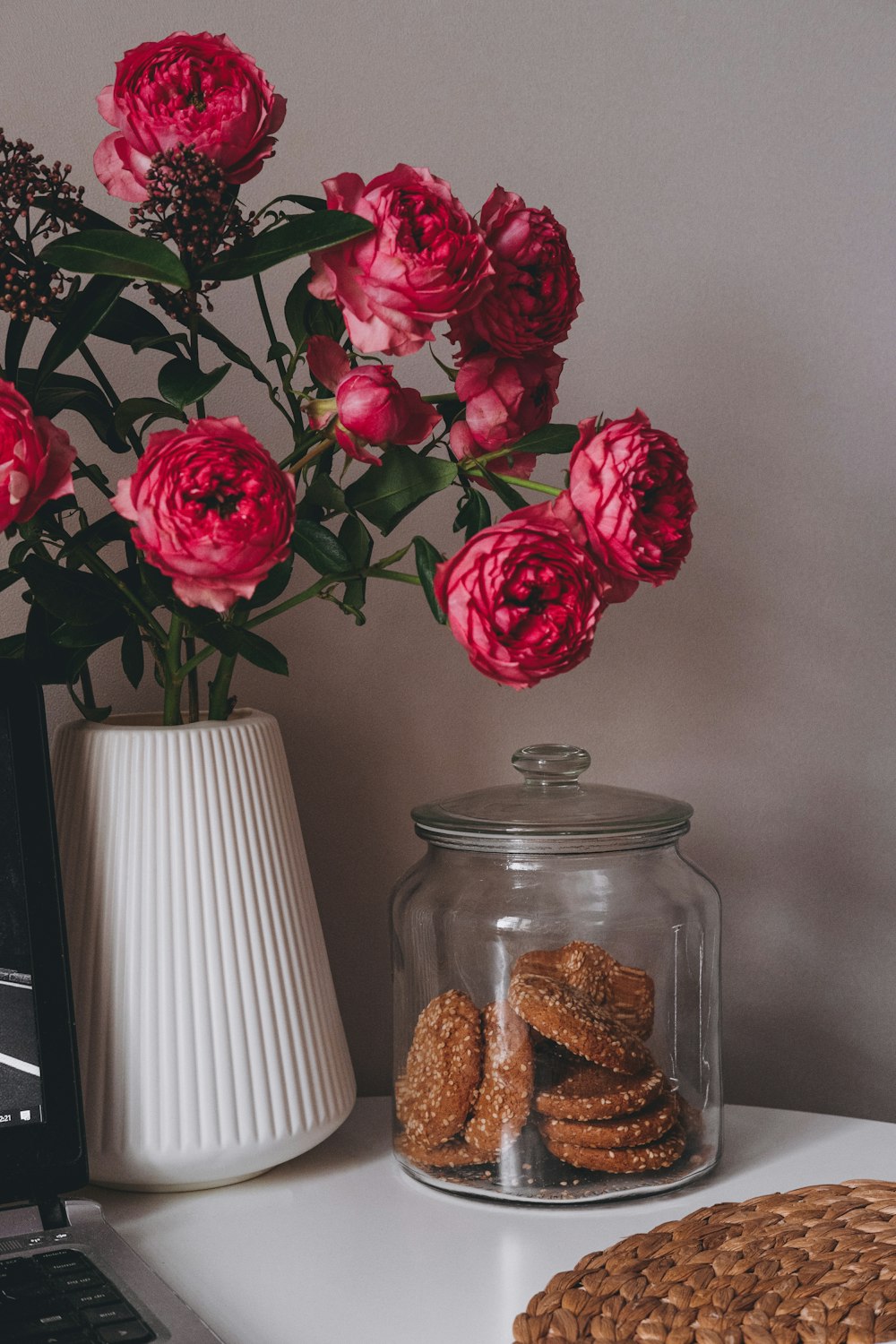 a vase filled with pink flowers next to a laptop