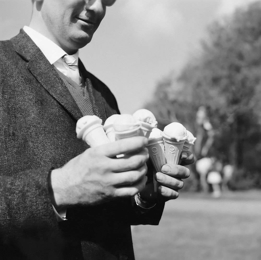 a man in a suit holding three ice cream cones