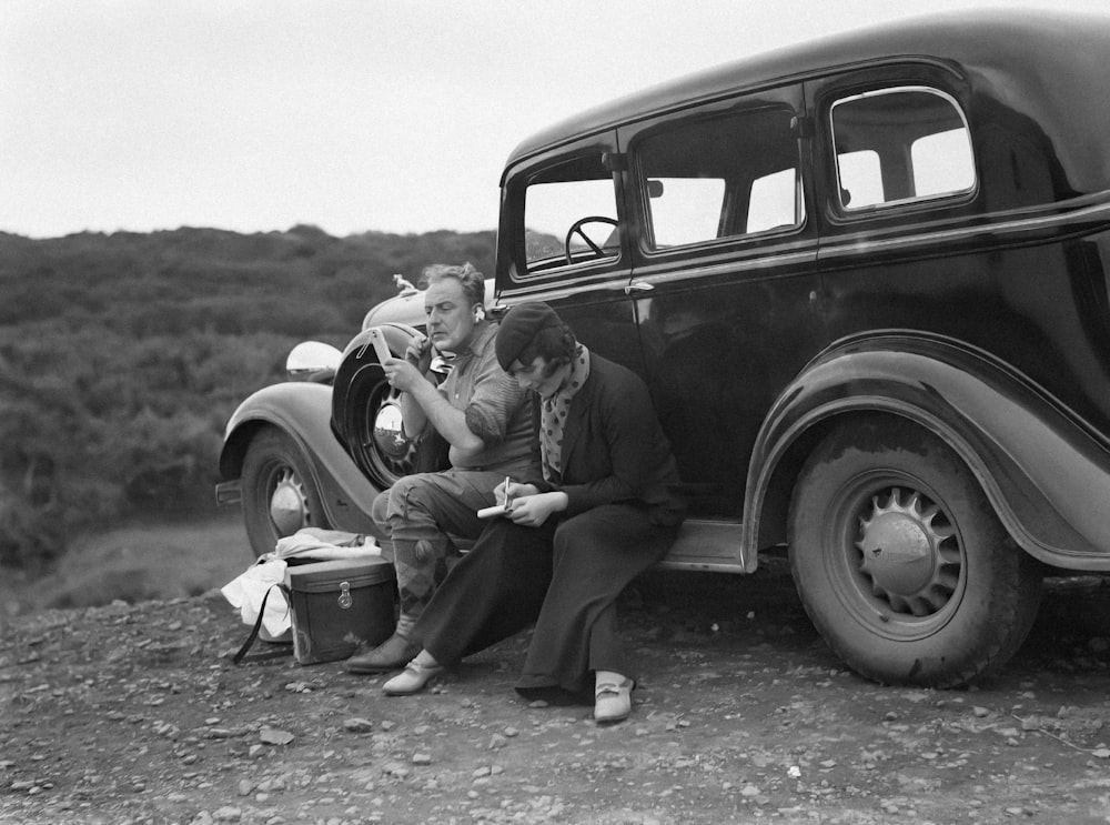 a man and a woman sitting on the back of a car