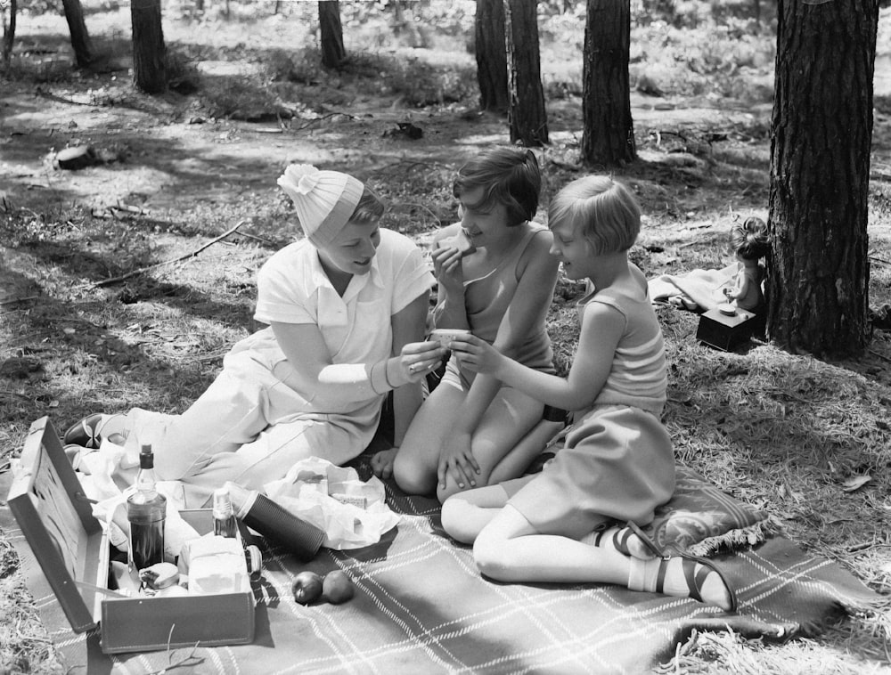 a group of people sitting on a blanket in the woods