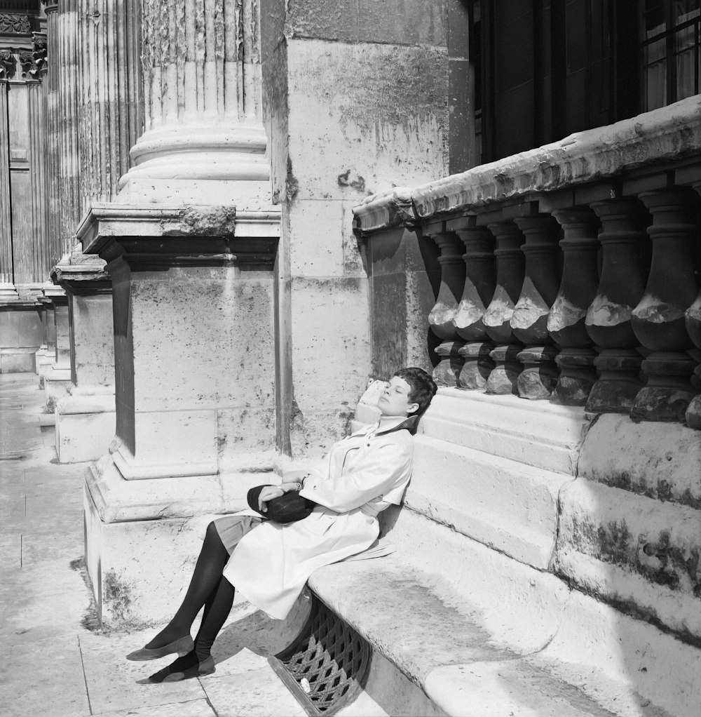 a black and white photo of a woman sitting on a bench