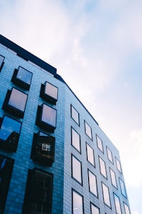 Sophisticated office building exterior in deep navy blue and slate grey tones under a clear sky.