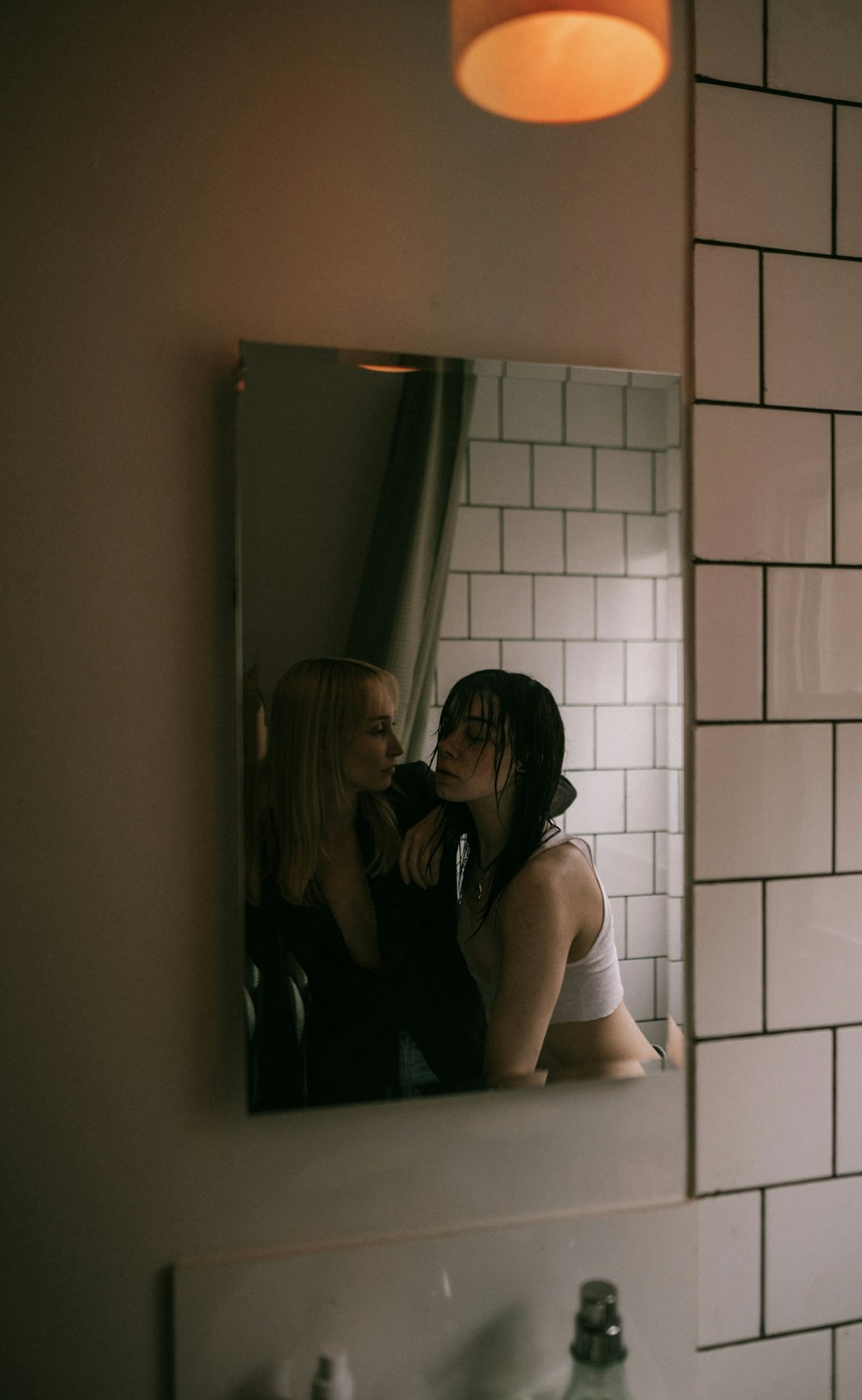 um casal de mulheres em pé na frente de um espelho do banheiro