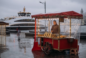 a man standing behind a food cart in the rain