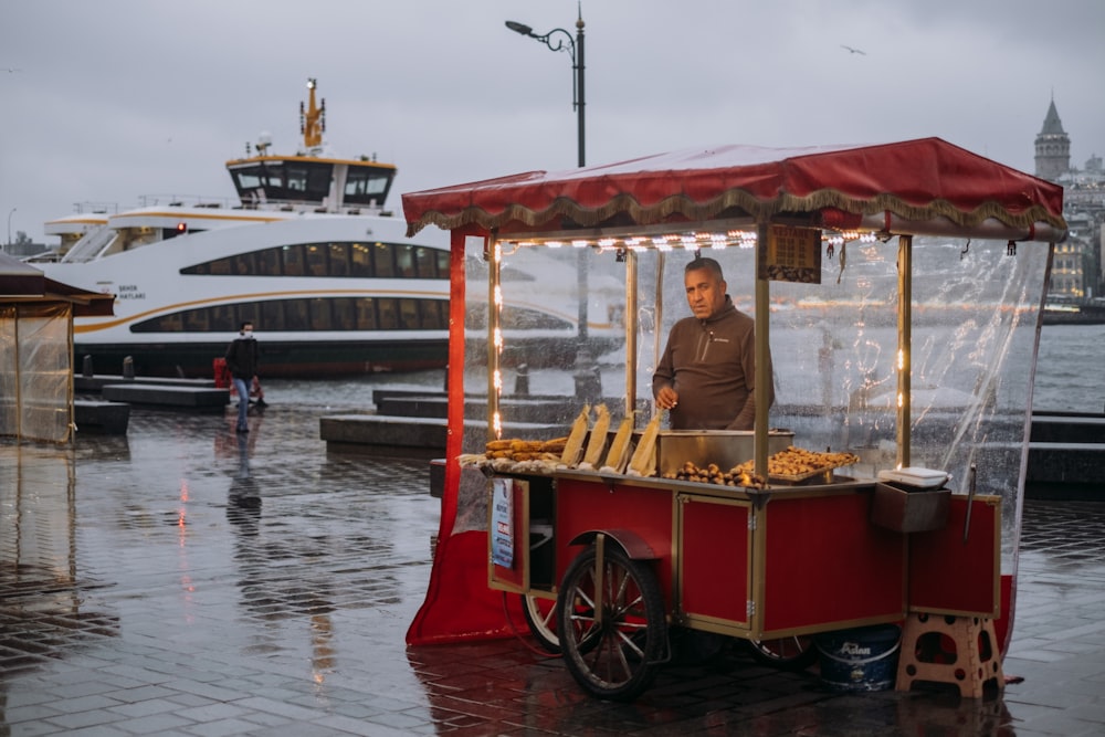 a man standing behind a food cart in the rain