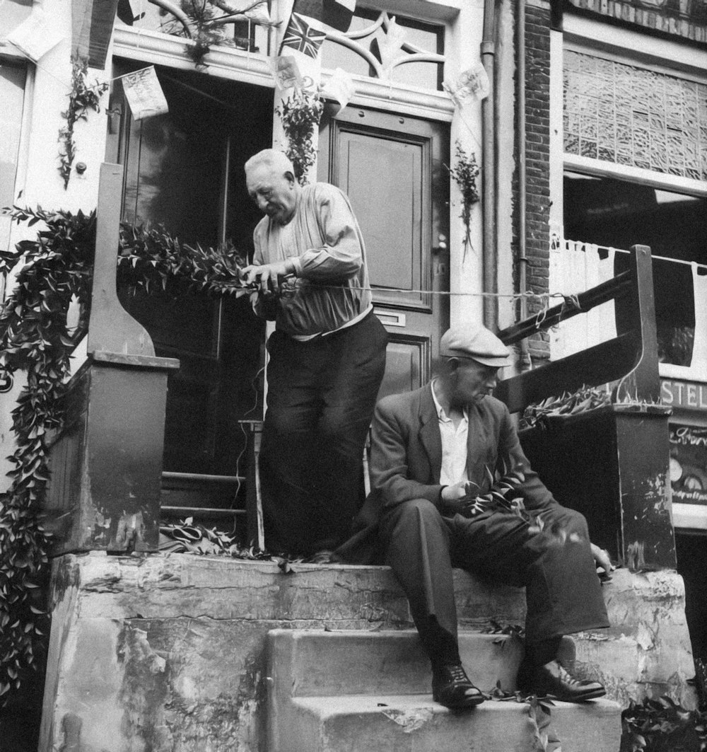a couple of men sitting on the steps of a building