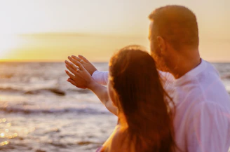 Joyful couple exchanging rings during a sunset beach wedding ceremony