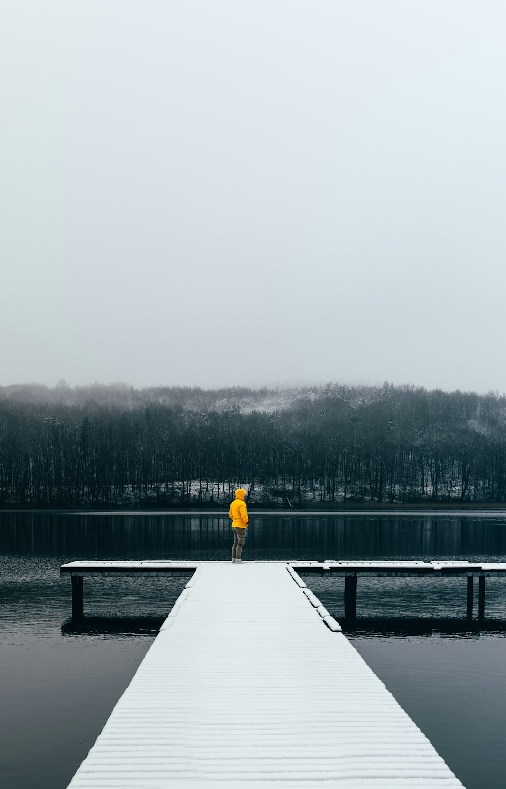 a person standing on a dock with a yellow umbrella