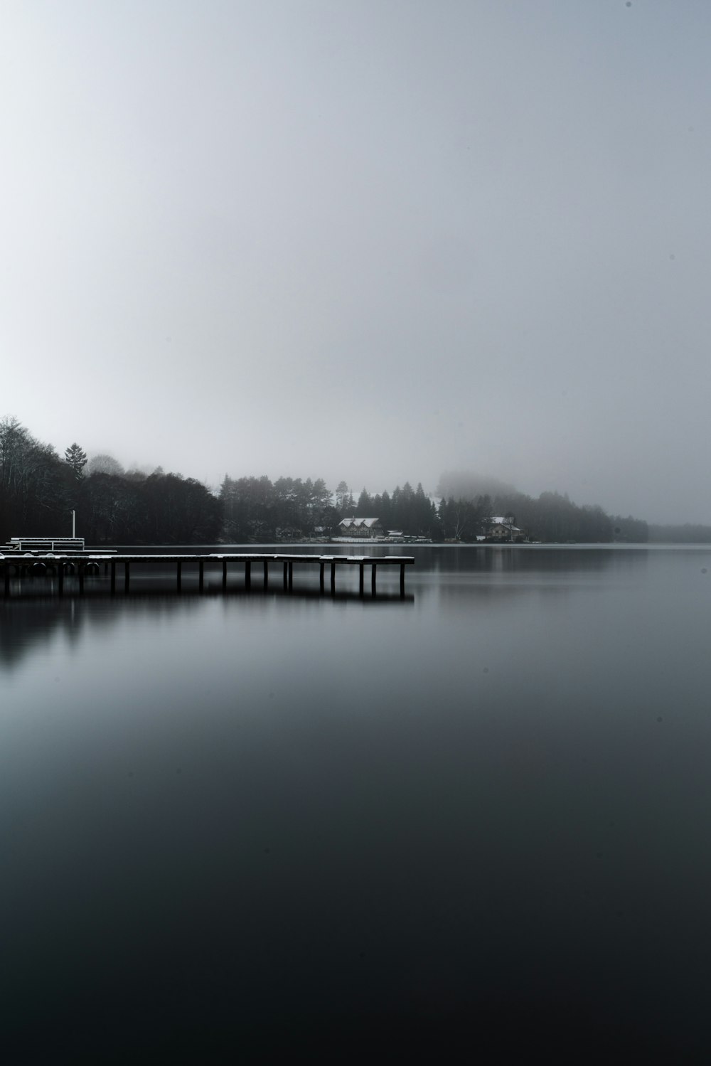 a long dock sitting on top of a lake next to a forest