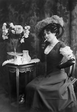 a woman sitting at a table with a vase of flowers