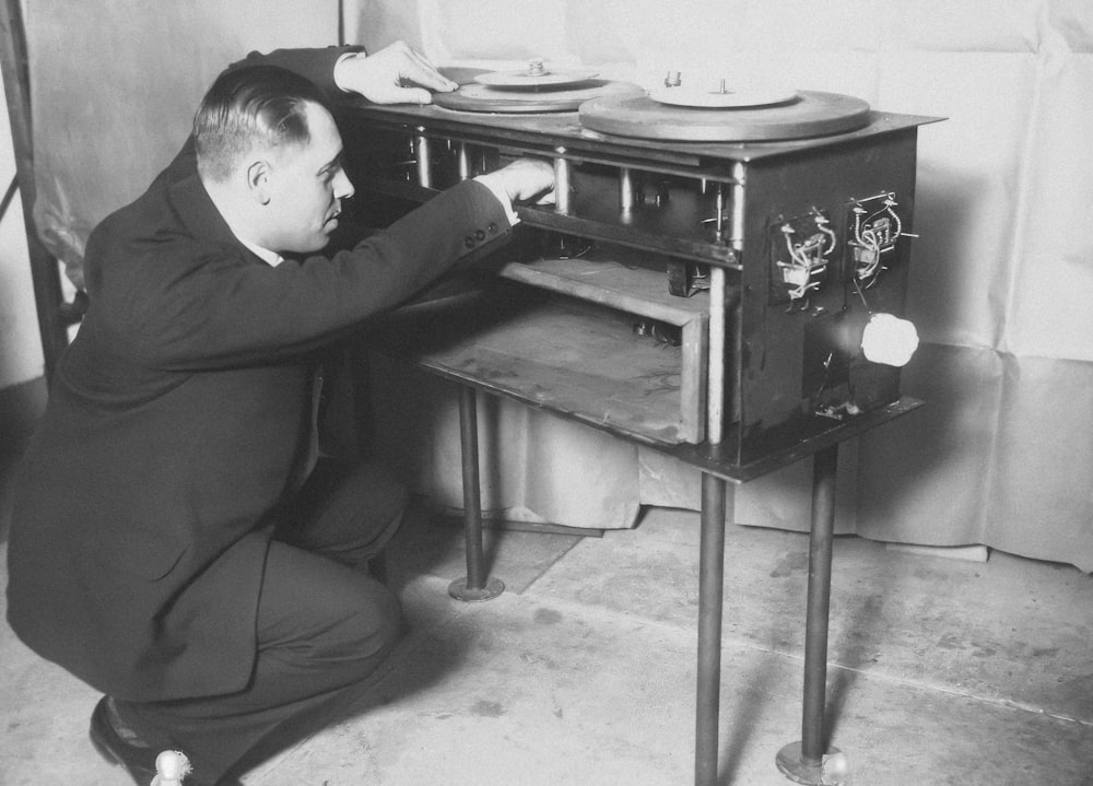 a man kneeling down next to an old fashioned stove