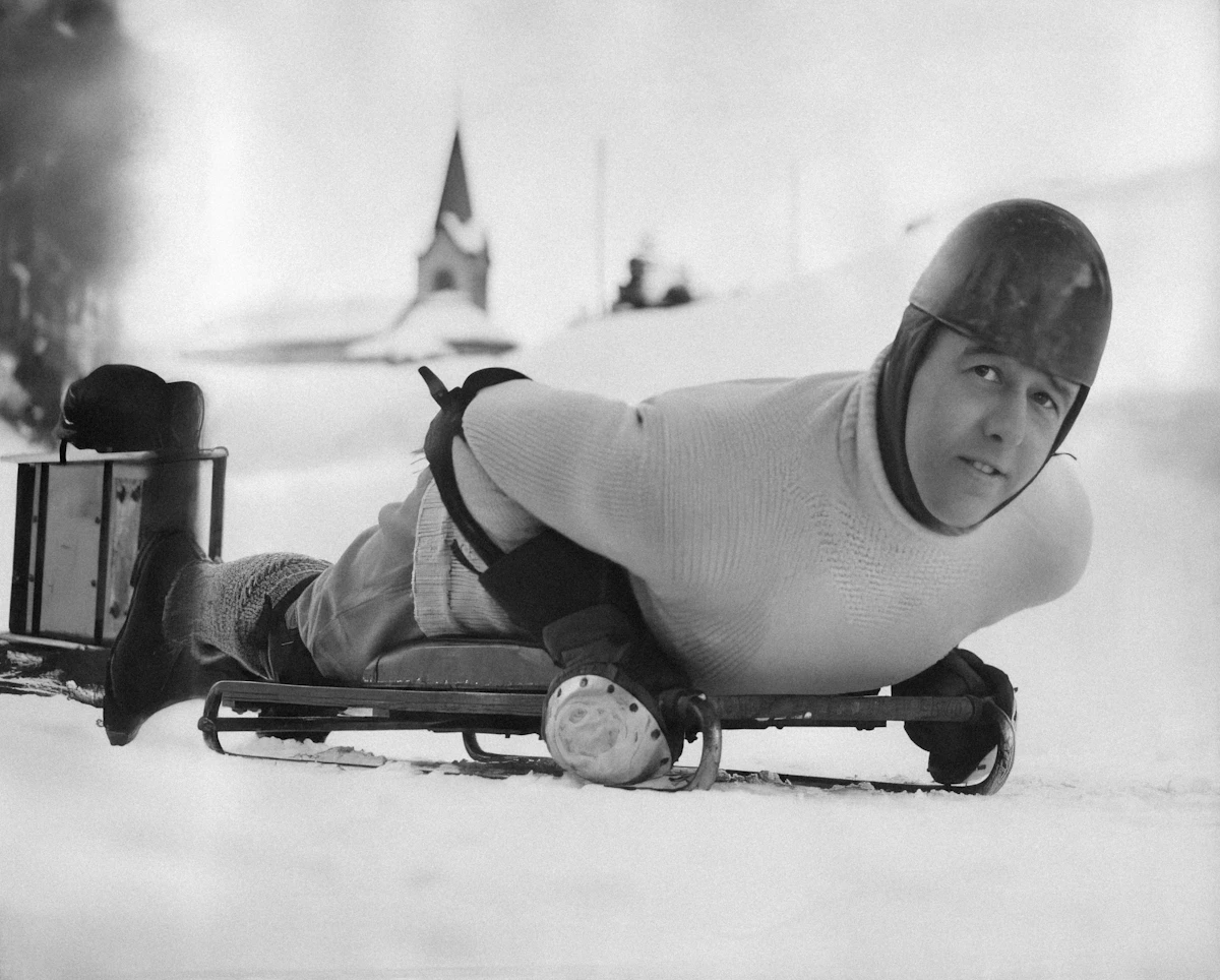 a man riding a sled down a snow covered slope