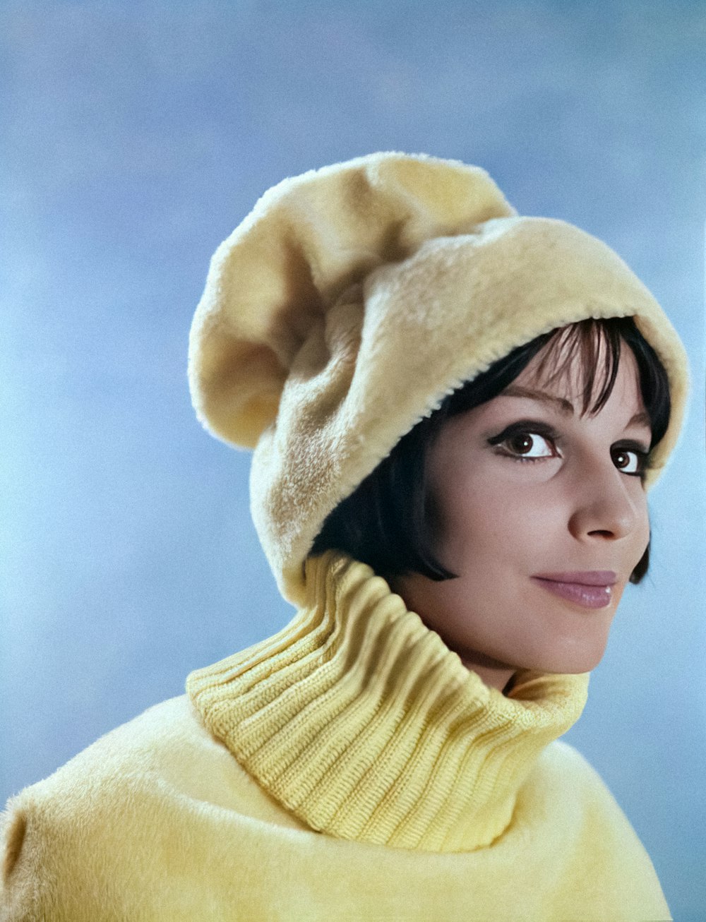 a woman wearing a yellow sweater and a hat