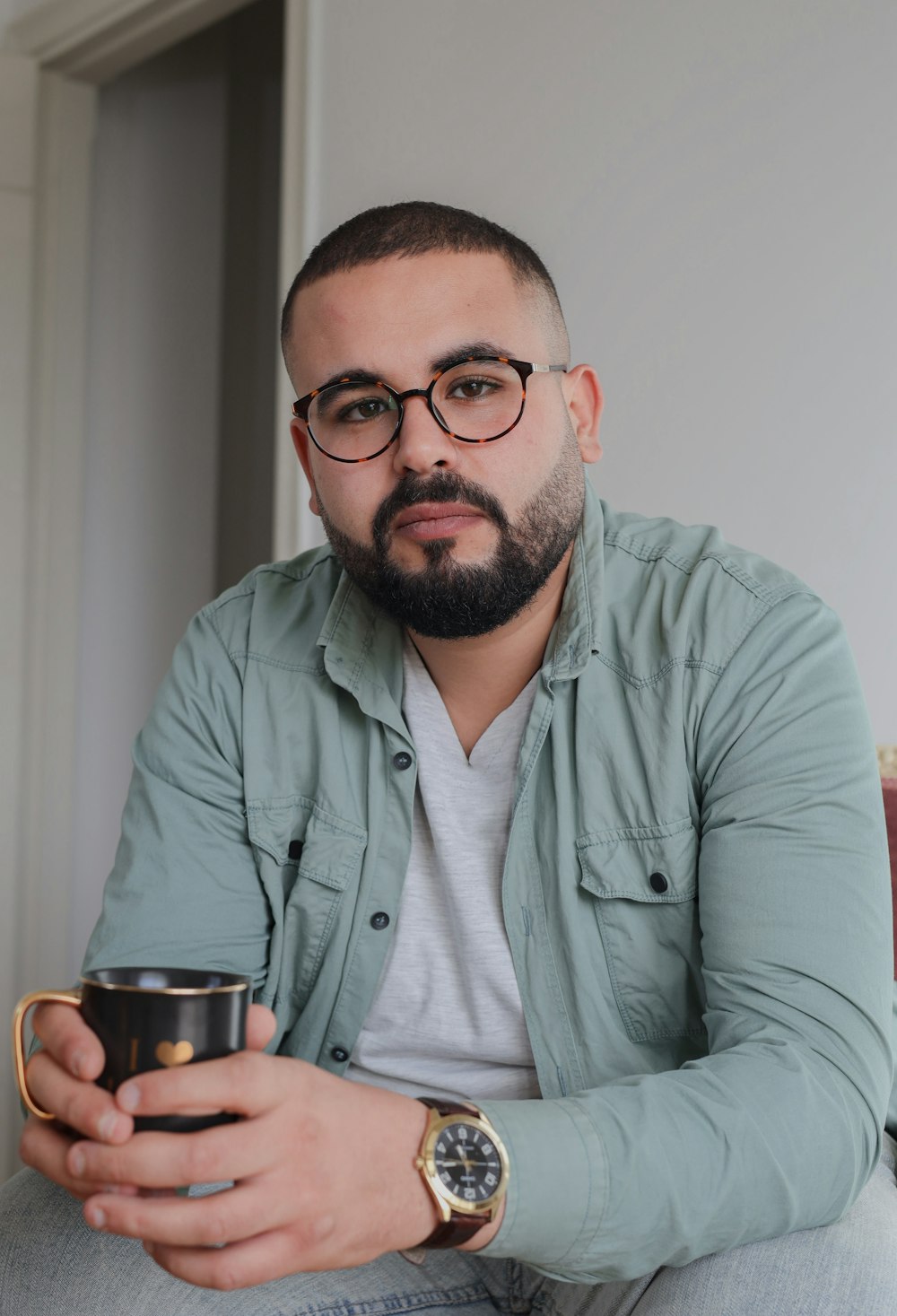 a man sitting on a couch holding a coffee cup