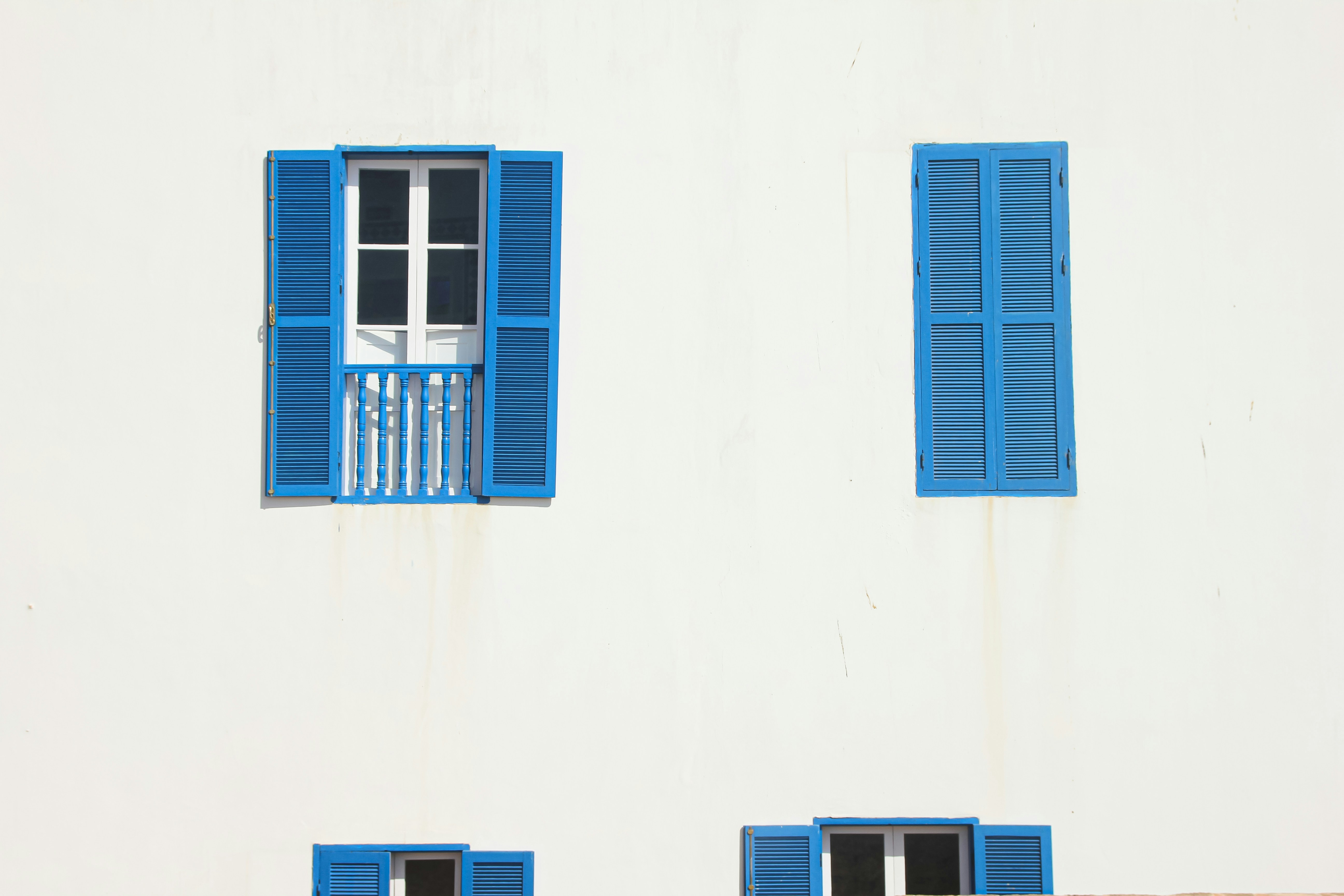 a white building with blue shutters and a clock