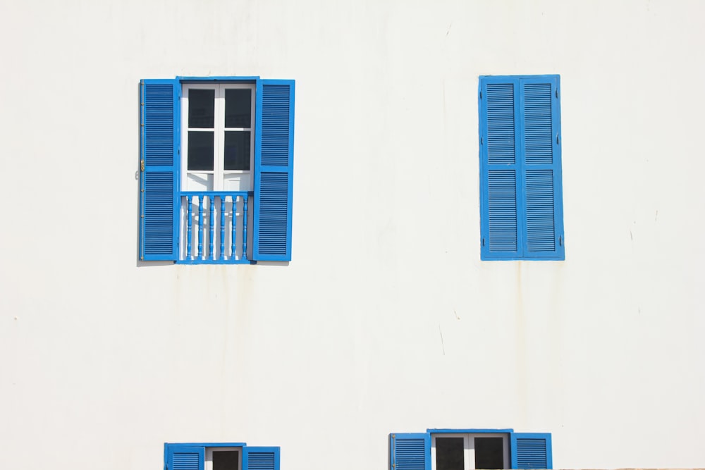 a white building with blue shutters and a clock