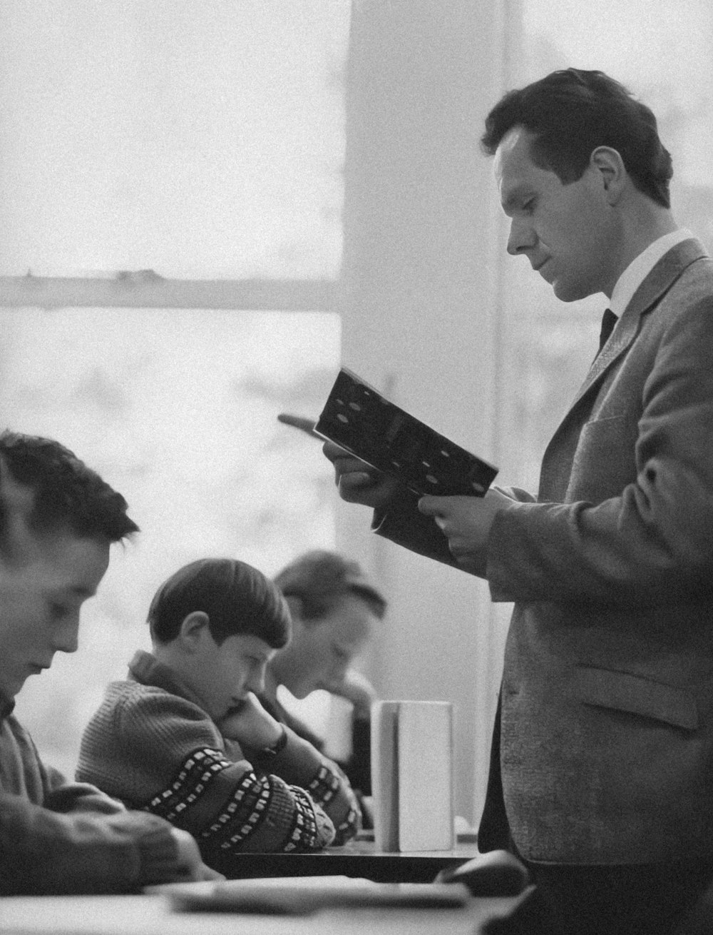 a black and white photo of a man reading a book