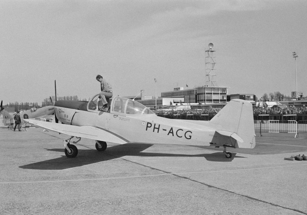 a black and white photo of a man standing on top of a plane