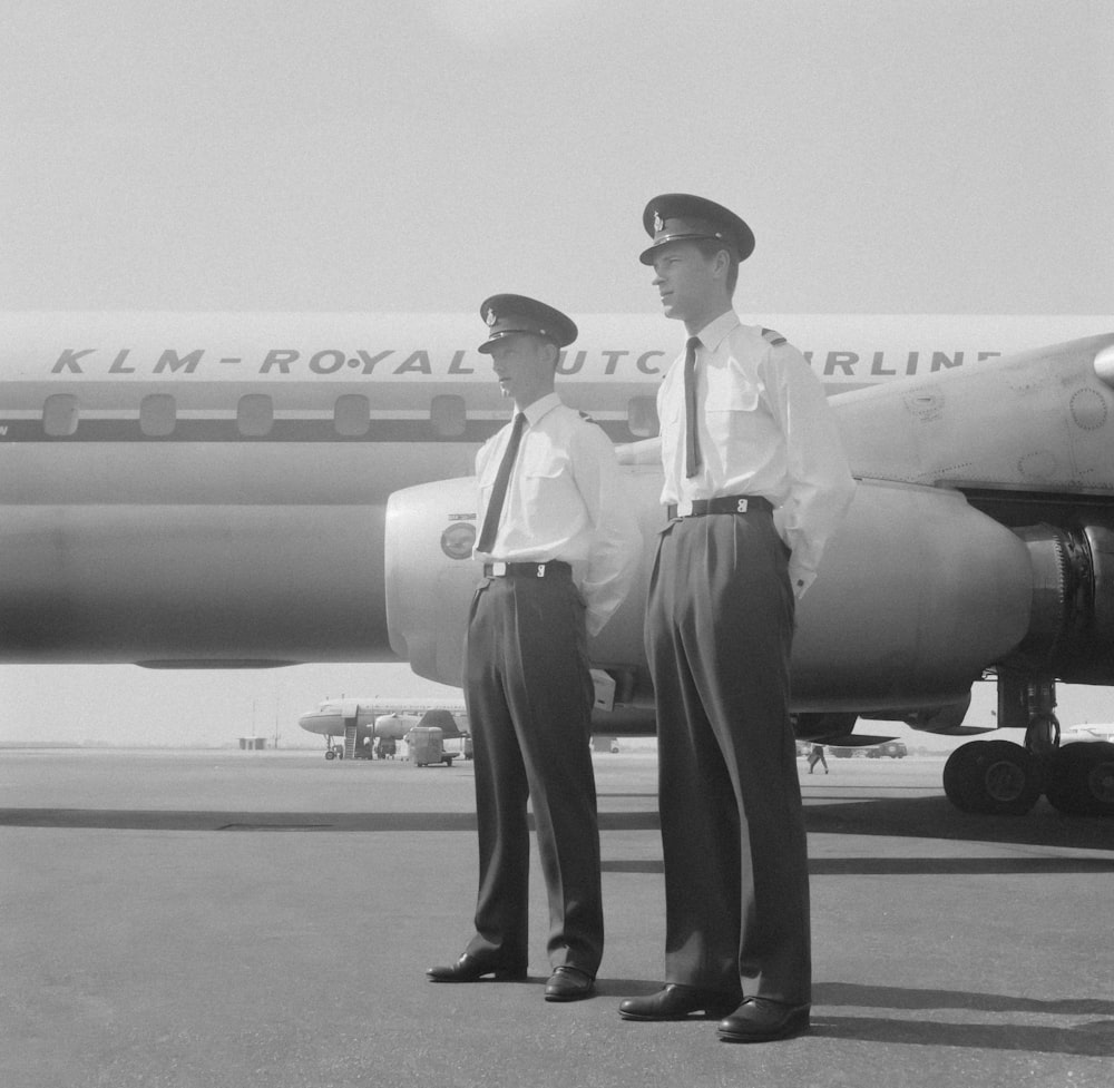 dois homens em pé na frente de um avião