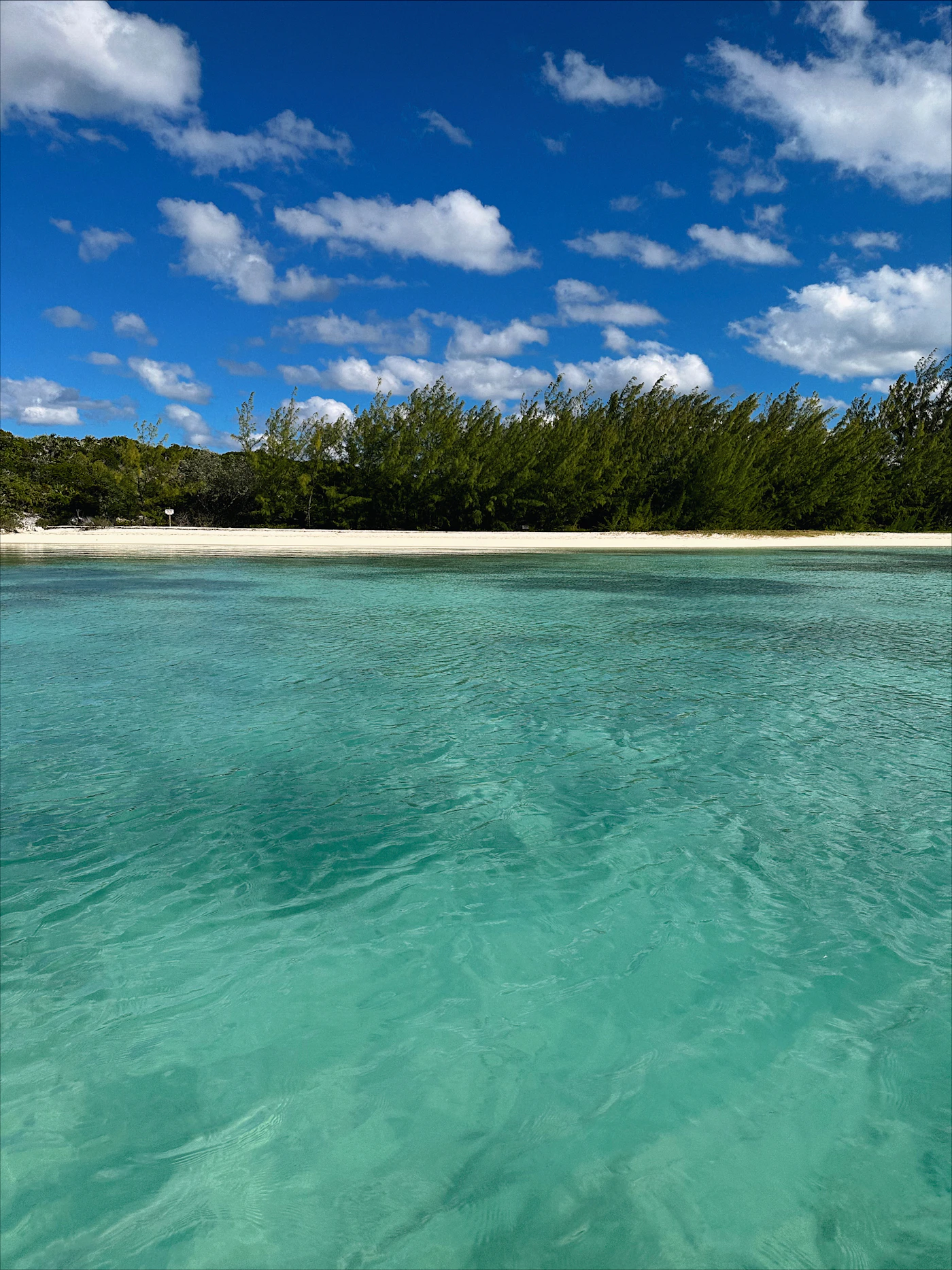 Crystal clear turquoise water in the Bahamas with the sand and coral visible through the shallow water and the deeper blue of the Bahamian banks beyond
