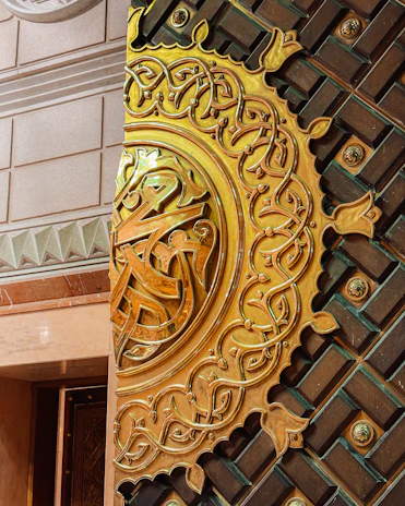 Close-up of an ornate fragrance box featuring intricate Islamic geometric patterns in gold and turquoise.
