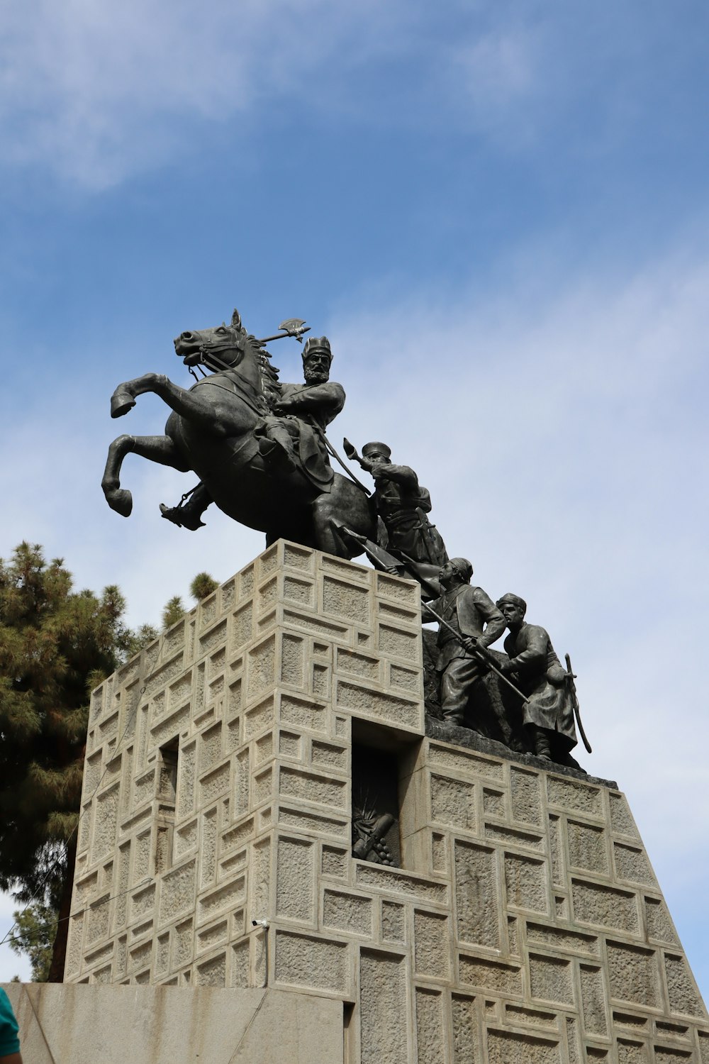 uma estátua de um homem montando um cavalo com um grupo de pessoas sobre ele