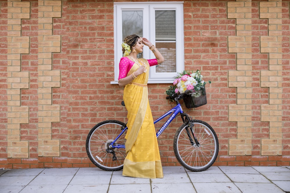 a woman in a yellow sari standing next to a bike