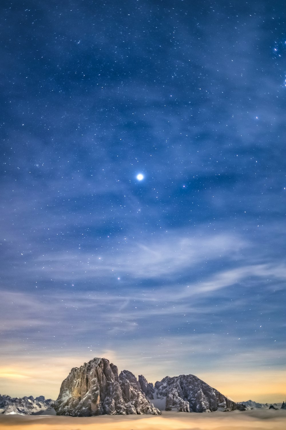 the night sky with stars above a mountain range