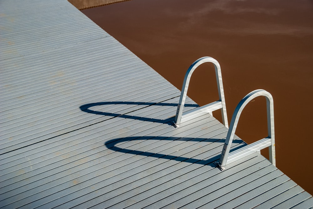 a metal railing on a wooden dock next to a body of water