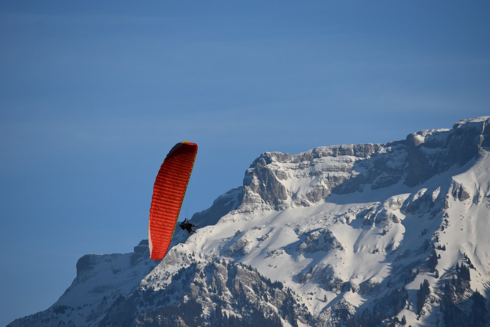 a paraglider flying over a snow covered mountain