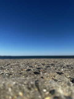 A wide shot of a newly finished concrete driveway with clear blue sky in the background.