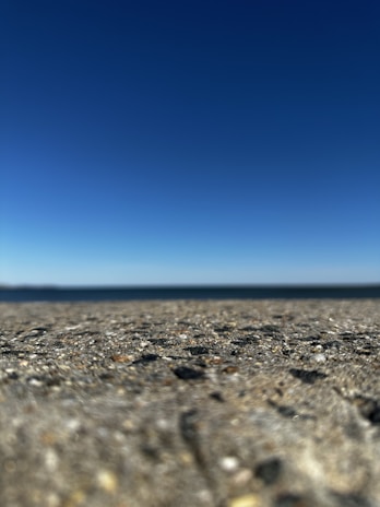A wide shot of a newly finished concrete driveway with clear blue sky in the background.