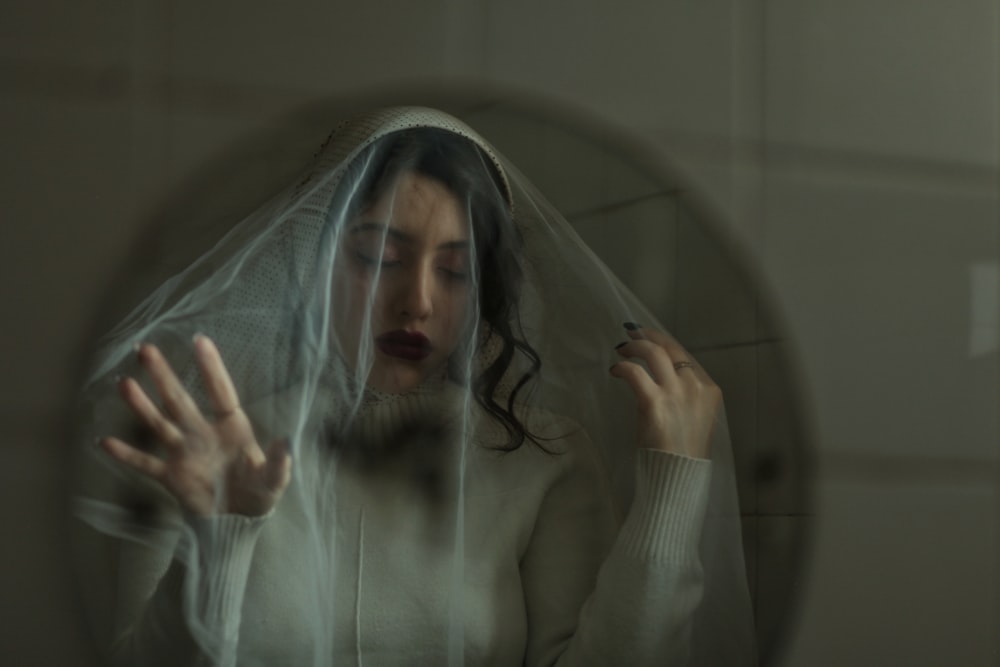 a woman wearing a veil looking at herself in a mirror