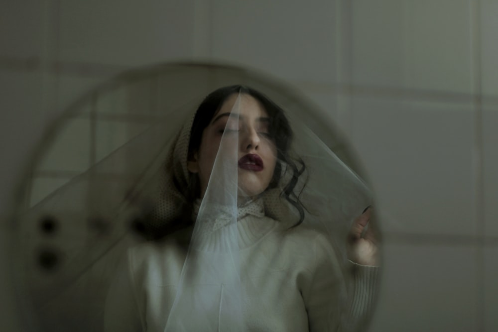 a woman wearing a veil looking at herself in a mirror