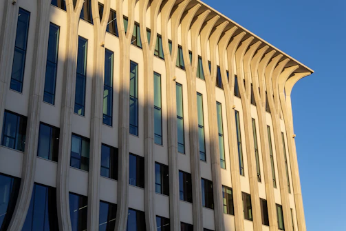 Sunlit modern architectural facade showcasing sleek Divyalux™ exterior cladding in warm natural tones.
