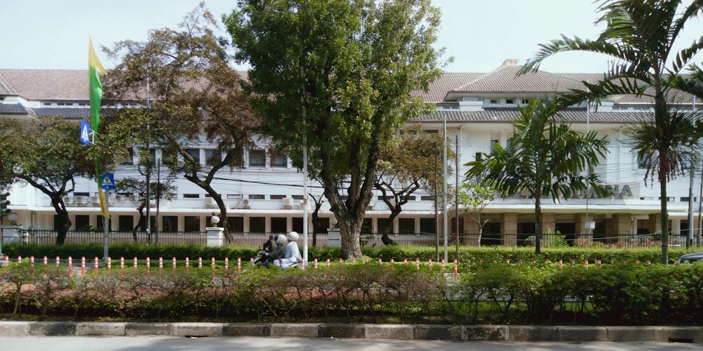 a large white building sitting next to a lush green park